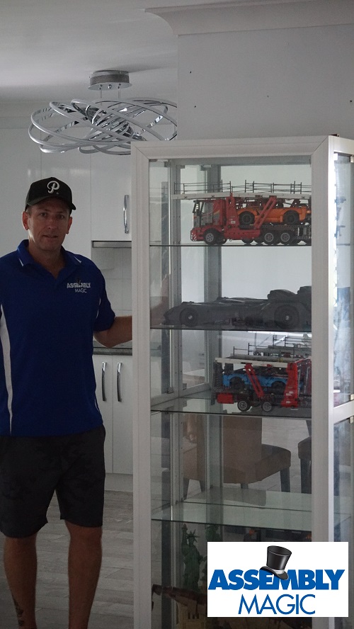 Technician - Ben, next to a Lego cabinet with Lego he assembled inside