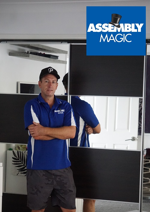 Technician - Ben in front of a flat pack wardrobe he just assembled. Assembly Magic logo in top right corner