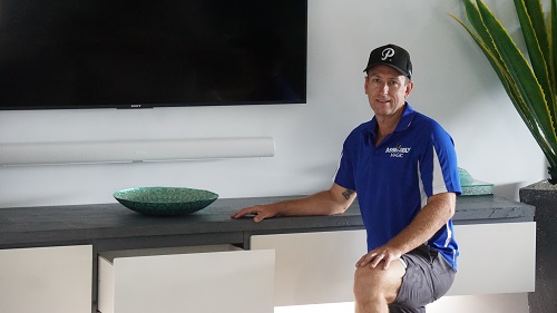 Technician - Ben in front of a floating cabinet he installed in a living room