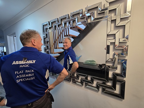 Technician looking into a mirror he hung for a client.