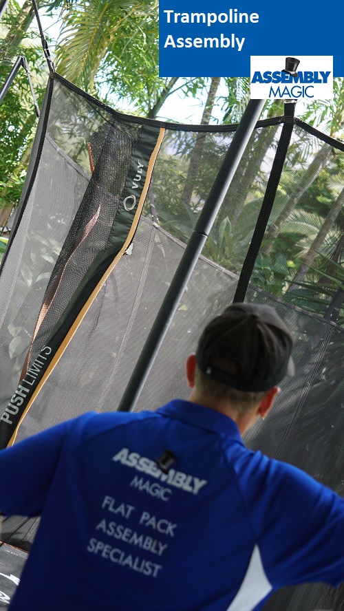 Technician - Ben, with the back of his shirt showing in front of a trampoline he assembled