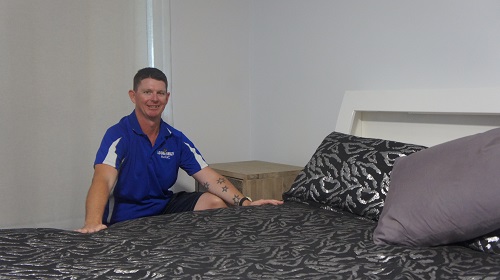Technician - Brendan, next to a bed he assembled
