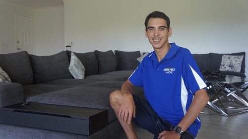 Technician - Shaun kneeling next to a couch