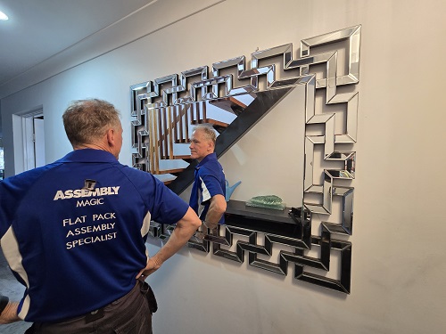 Technician posing in front of a mirror he hung on a wall in a Rochedale home.