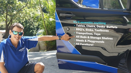 Shaun pointing out his services on the door of his van.