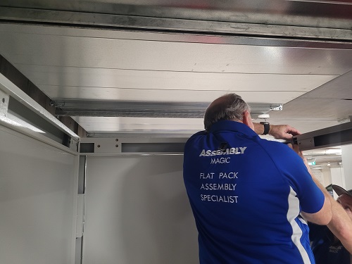 Technician installing over bonnet storage unit