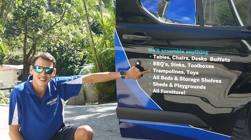Technician - Shaun, pointing to his services on the side of his van.