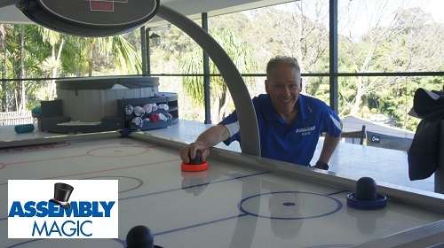 Technician with an air hockey table he installed. Logo in bottom left corner