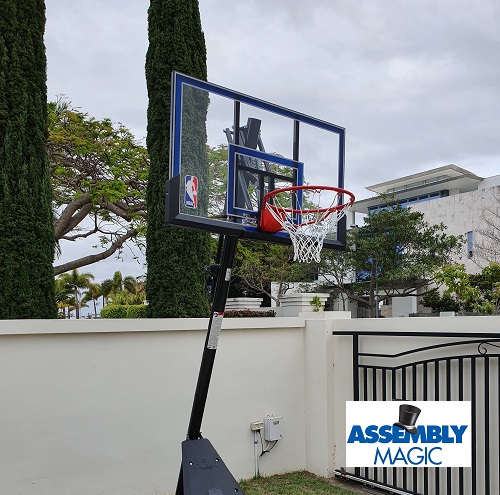 Big portable basketball hoop with Assembly Magic logo in bottom right corner